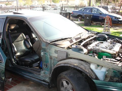 1993 Ford Taurus - A green sedan, possibly a 1993 Ford Taurus, is shown with its hood open and front fender damaged.