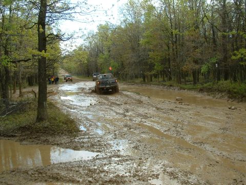 1991 Ford Bronco - Off-road vehicles tackle a challenging muddy track during an outing.