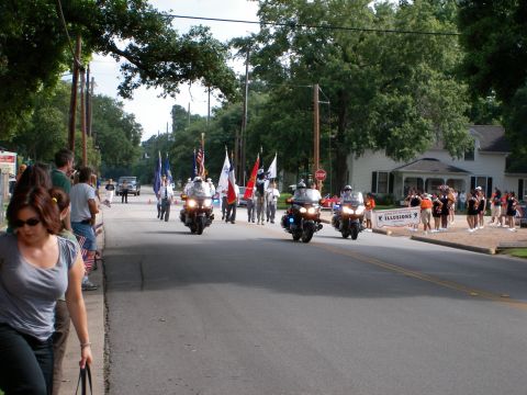 2000 Ford Crown Victoria - Motorcycle police escort a parade down a residential street, with spectators lining the sidewalk.