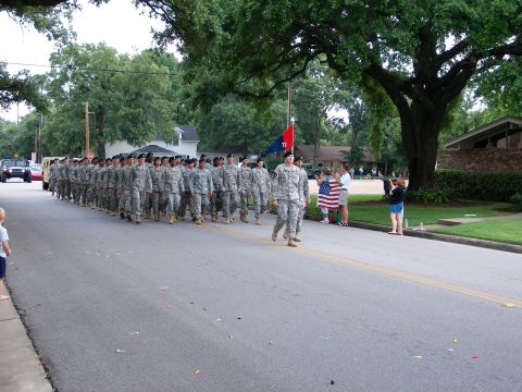 2000 Ford Crown Victoria - A military parade proceeds down a suburban street, observed by onlookers.
