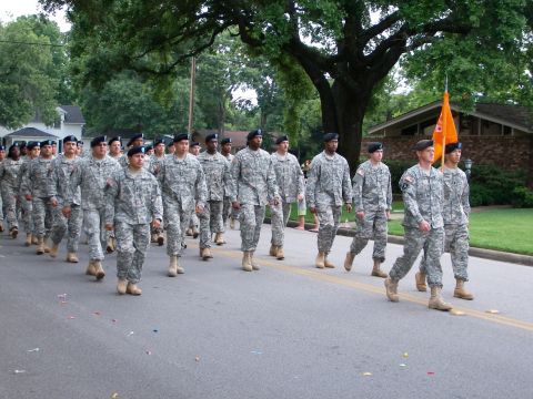 2000 Ford Crown Victoria - Soldiers march in formation during a parade, carrying an orange flag.