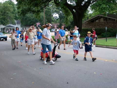 2000 Ford Crown Victoria - A blue car participates in a parade alongside marchers and spectators.