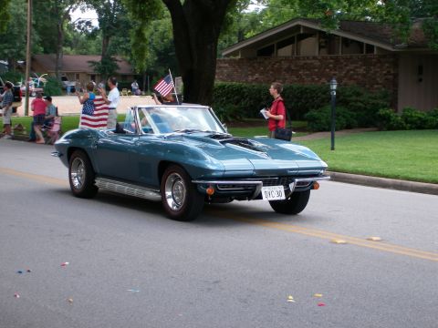 2000 Ford Crown Victoria - Classic teal Corvette convertible participates in a parade, flying an American flag.