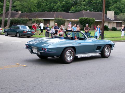 2000 Ford Crown Victoria - A classic blue convertible cruises down the street during a parade with spectators watching from the side.