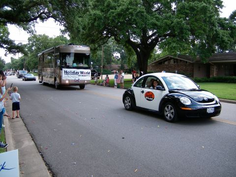 2000 Ford Crown Victoria - A black and white Volkswagen Beetle drives down a street, with a large RV in the background.