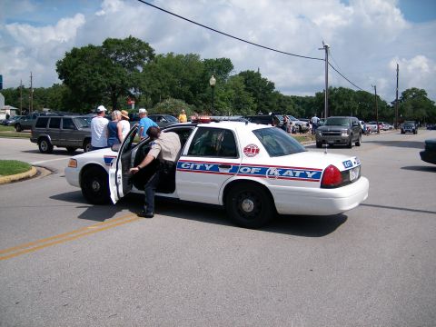2000 Ford Crown Victoria - A police officer exits a white patrol car marked "CITY OF KATY" during an outdoor event.