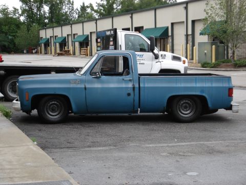 1979 Chevrolet C/K Pickup - A blue 1979 Chevrolet C/K Pickup truck is parked next to a white commercial truck.