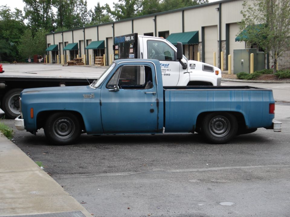 Lowered faded blue square-body Chevrolet long-bed pickup, driver side view