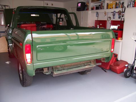 1978 Ford Bronco - Rear view of a green 1978 Ford Bronco with its hood and door open, parked inside a garage.