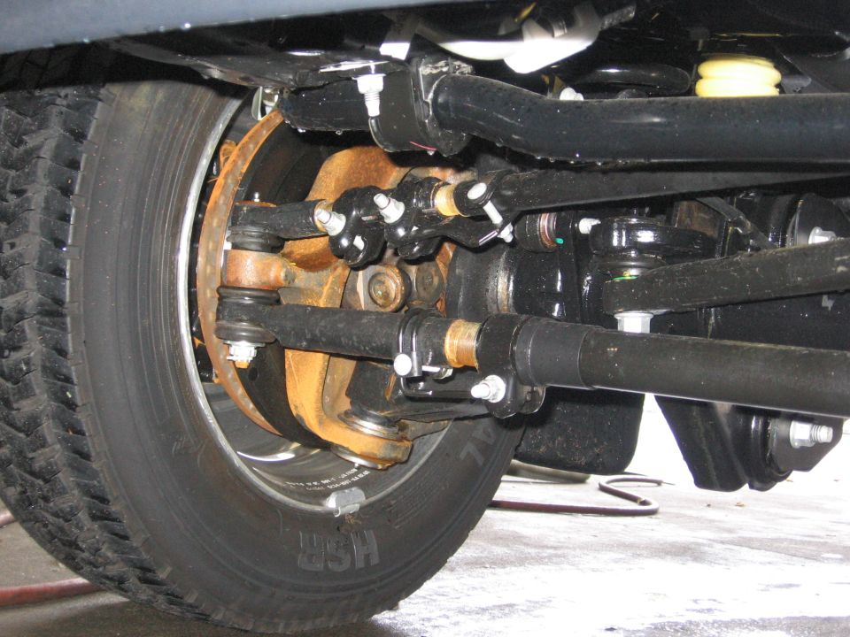 Close-up of truck's front wheel, brake rotor, and steering linkage