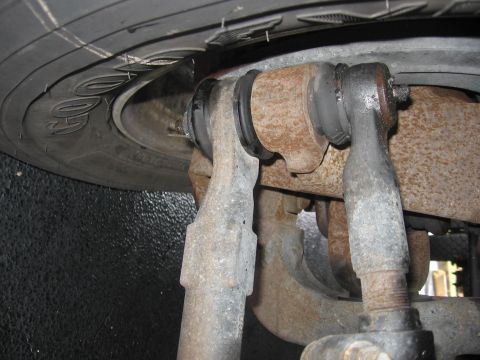 1974 Ford F-100 - Underside view of a vehicle's steering linkage, showing worn parts and a tire.
