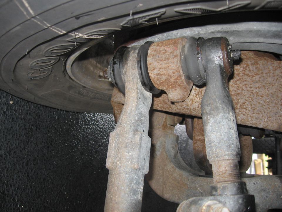 Close-up of rusty steering linkage components and tire tread