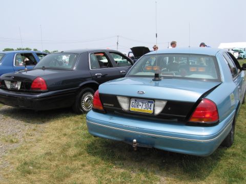 1991 Ford LTD Crown Victoria - A light blue police car is seen from the rear, parked next to a dark blue vehicle.