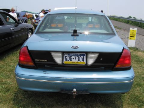 1991 Ford LTD Crown Victoria - Blue Ford Crown Victoria Police Interceptor parked on grass, with other vehicles and tents in the background.
