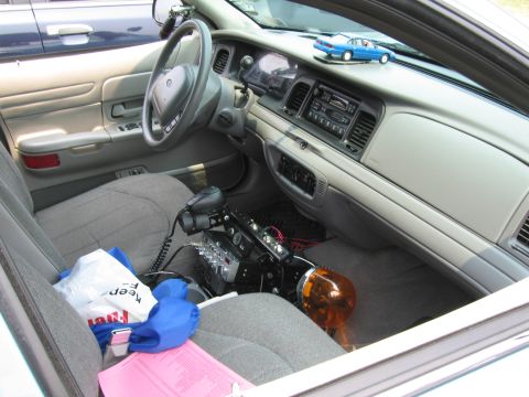 1991 Ford LTD Crown Victoria - The interior of a police car is shown, a radio and emergency light mounted on the center console.