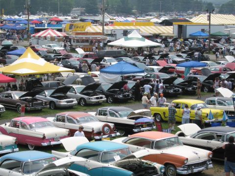 1991 Ford LTD Crown Victoria - A bustling outdoor car show features a wide array of vehicles and tents, suggesting a large gathering of automotive enthusiasts.