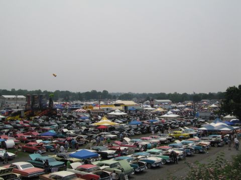 1991 Ford LTD Crown Victoria - A large gathering of vehicles and people at an outdoor event, with tents and trees in the background.