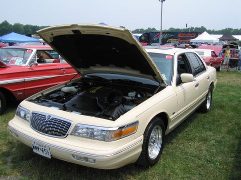 1991 Ford LTD Crown Victoria - A cream-colored Mercury Grand Marquis is displayed with its hood open at an outdoor car show.