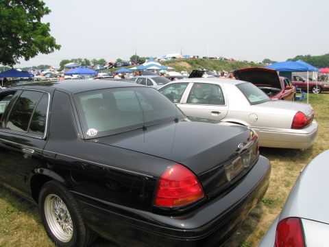1991 Ford LTD Crown Victoria - A black sedan is parked next to a silver sedan at an outdoor car show.