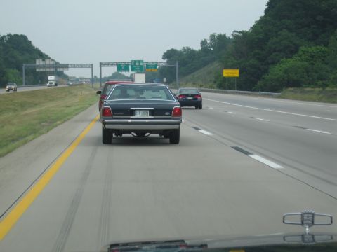 1991 Ford LTD Crown Victoria - Rear view of a 1991 Ford Crown Victoria LTD on the highway, with other vehicles visible.