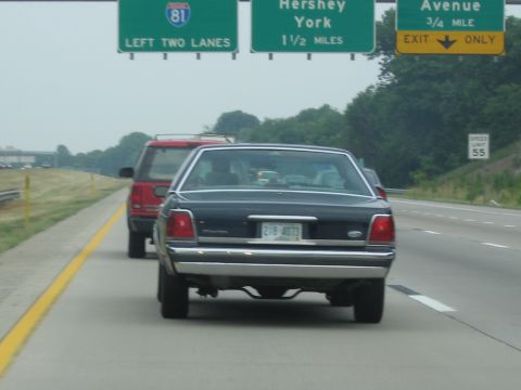 1991 Ford LTD Crown Victoria - Driving on the highway behind a red SUV, with highway signs indicating upcoming exits.