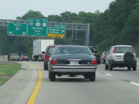 1991 Ford LTD Crown Victoria - A black 1991 Ford Crown Victoria LTD drives on a highway, with other vehicles and highway signs visible.