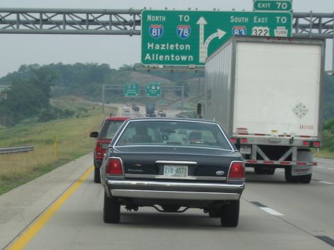 1991 Ford LTD Crown Victoria - A 1991 Ford Crown Victoria LTD is seen from behind on a highway, with a semi-truck to its right and a red SUV ahead.