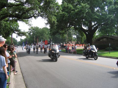 2000 Ford Crown Victoria - Motorcycles lead a parade down a tree-lined street with spectators watching.