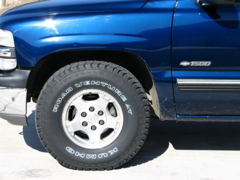 2001 Chevrolet Silverado 1500 - Close-up of the front wheel and side panel of a blue 2001 Chevrolet Silverado 1500 pickup.