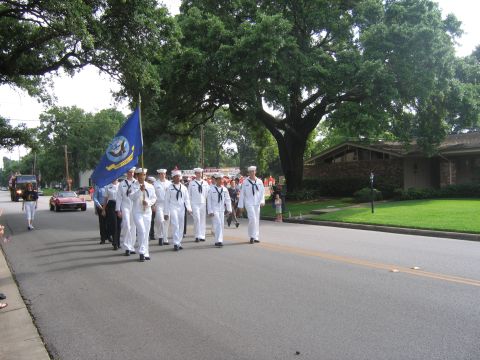 2000 Ford Crown Victoria - A group of US Navy sailors participate in a parade, marching down a residential street.