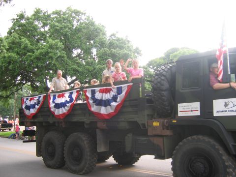 2000 Ford Crown Victoria - A military truck carries passengers during a parade, adorned with patriotic decorations.