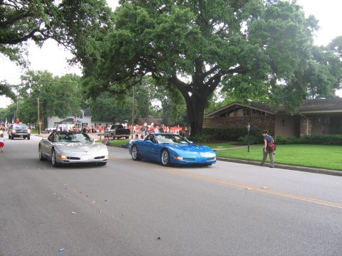 2000 Ford Crown Victoria - Two Chevrolet Corvettes participate in a parade, with spectators lining the street.
