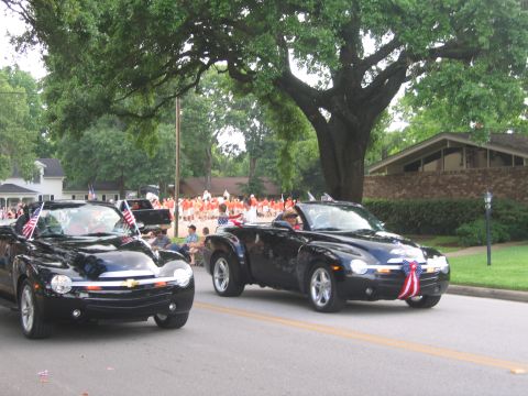 2000 Ford Crown Victoria - Two black Chevrolet SSR pickup trucks participate in a parade, adorned with patriotic decorations.