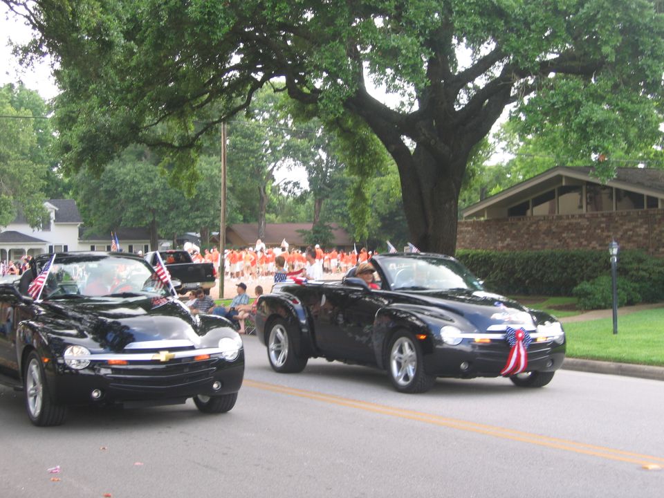 Two black Chevrolet SSR pickup trucks decorated with American flags in a parade