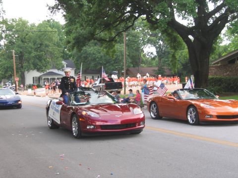 2000 Ford Crown Victoria - A military member rides in a convertible during a parade, with another Corvette following behind.