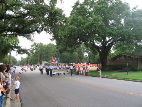 2000 Ford Crown Victoria - A parade is underway with spectators lining the street and a marching band in formation.