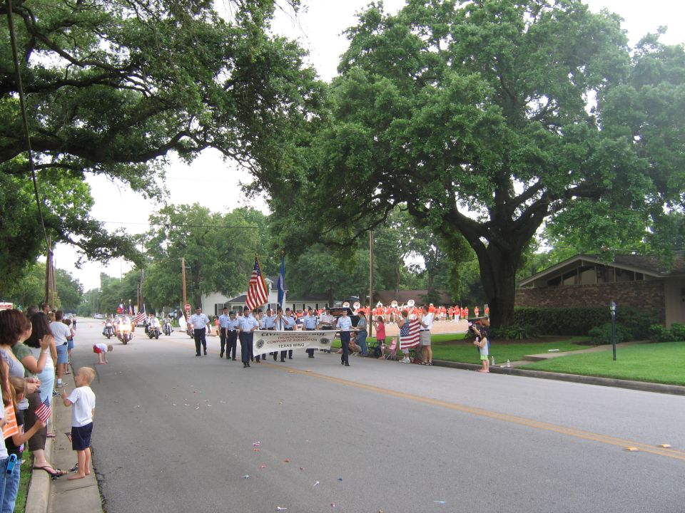 Parade scene with people watching, a marching band, and motorcycles on a street