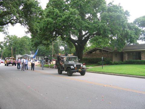 2000 Ford Crown Victoria - A military police jeep participates in a parade, with onlookers and other vehicles in the background.
