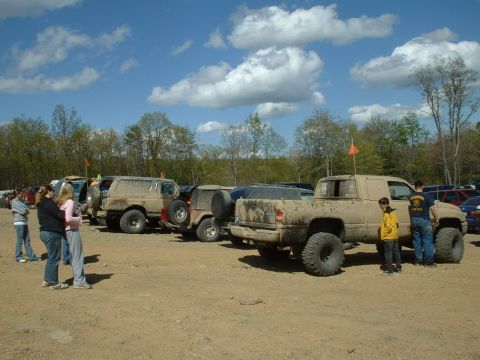 1991 Ford Bronco - Off-road vehicles are parked in a lot, some appearing muddy from recent use.