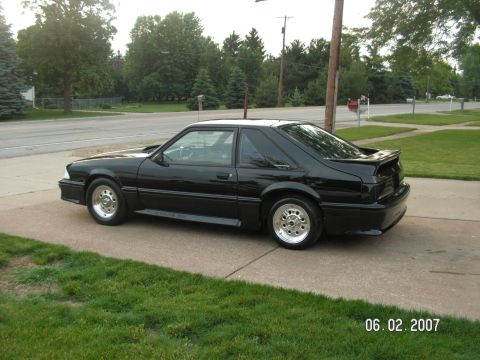 1988 Ford Mustang - A black 1988 Ford Mustang coupe is parked on a driveway, viewed from the rear three-quarter angle.