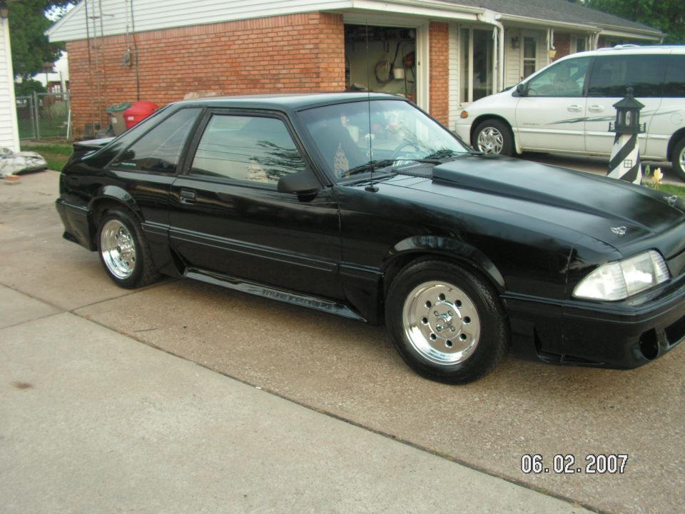black coupe with a cowl induction hood parked in a driveway