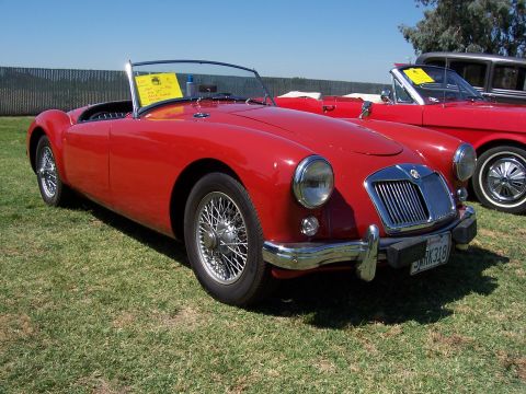 2002 Ford Mustang - A red MGA convertible is parked on grass next to another red car.