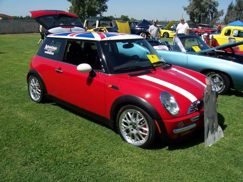 2002 Ford Mustang - A red Mini Cooper with a Union Jack roof and white racing stripes is parked on grass at a car show.