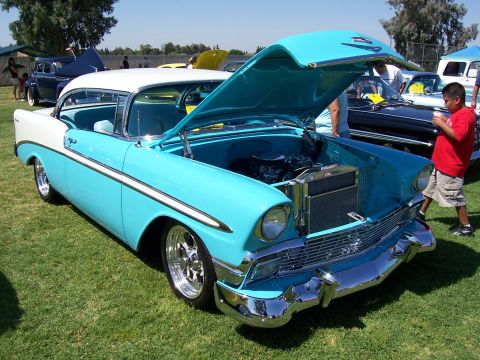 2002 Ford Mustang - A classic 1956 Chevrolet Bel Air, painted in a striking two-tone blue and white, is displayed with its hood open at an outdoor car show.