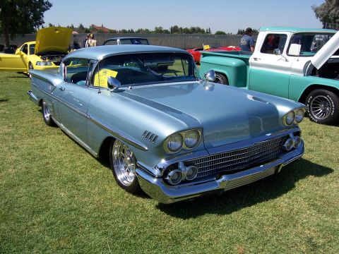 2002 Ford Mustang - A light blue 1958 Chevrolet Bel Air is parked on grass next to other vehicles.
