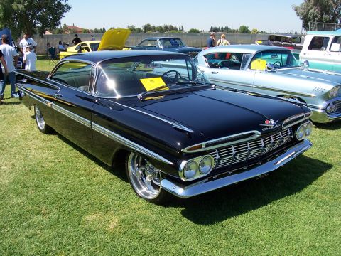 2002 Ford Mustang - A classic black 1959 Chevrolet Impala is displayed at an outdoor car show with other vintage vehicles.
