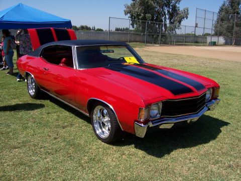 2002 Ford Mustang - A classic red muscle car with black racing stripes is displayed outdoors on a sunny day.