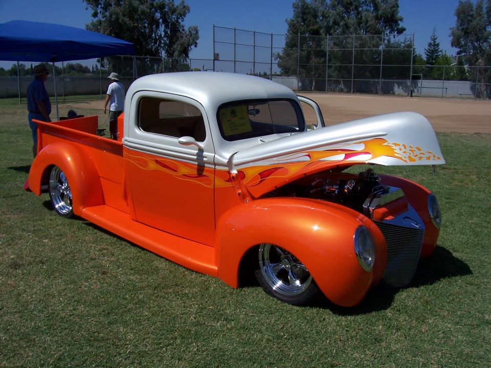Orange and silver custom pickup truck with flames, hood open, on grass