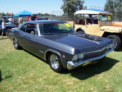 2002 Ford Mustang - A 1965 Chevrolet Impala coupe is parked on a grassy field next to another vehicle.