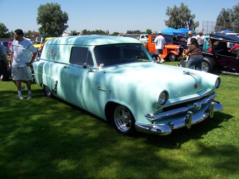 2002 Ford Mustang - A light blue sedan delivery van, likely a 1954 model, is displayed on a grassy field at an outdoor event.